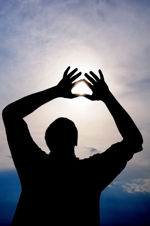 Male is holding the sun in his hands with heart symbolの写真素材