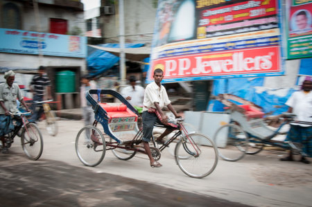 Delhi, India, August 14, 2011- Serious young rickshaw with blurred street on background, shot was...