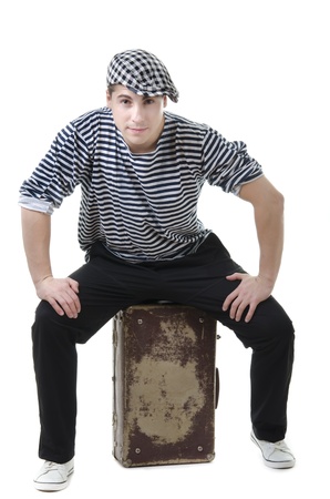 Look naughty handsome young man in stylish striped dress and cap with suitcaseの写真素材