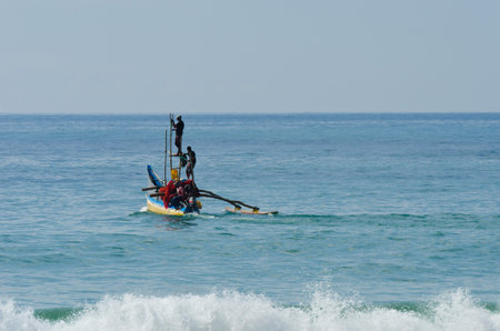 Mirissa, Sri Lanka - December 12, 2011: Traditional Asian small motorboat with four fishermen and...