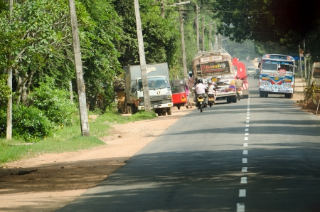 Habarana, Sri Lanka - December 6, 2011: Intensive traffic on a narrow asian street with regular buses covered by drawings, motobikes and cars.のeditorial素材