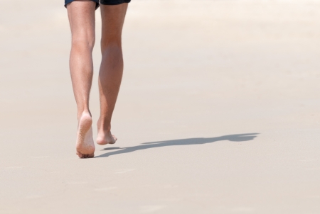Running bare legs of runner jogging on beach  Shallow depth of field, focus on left foot の写真素材