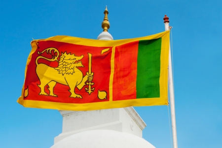 Sri Lanka flag on flagstaff with blue sky and traditional stupa on background の写真素材