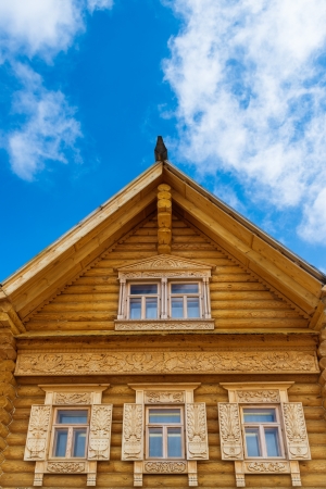 Fragment of a wooden blockhouse with ornamental windows on the blue sky background  Russian style  の写真素材