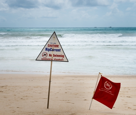 Warning signs about rip current at a beach with storm clouds on backgroundの写真素材