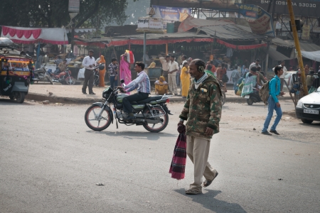AGRA, INDIA - NOVEMBER 15: AGRA, INDIA - NOVEMBER 15: Elderly indian pedestrian in warm clothes on typical messy street in central India on Nov 15, 2012 in Agra, India on Nov 15, 2012 in Agra, Indiaのeditorial素材