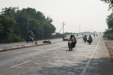 AGRA, INDIA - NOVEMBER 15: Motorcycles and tuk-tuks drive on covered by haze Ring road (Delhi - Agra) on Nov 15, 2012 in Agra, Indiaのeditorial素材