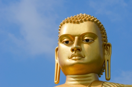 Golden yellow Buddha statue head on blue sky backgroundの写真素材
