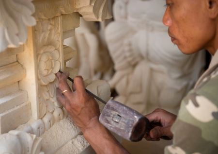 BALI, INDONESIA - SEP 21: Stone mason at work carving an ornamental relief on Sep 21, 2012 in Batubulan, Bali, Indonesia. Batubulan is a center of Balinese stone carvings art.のeditorial素材
