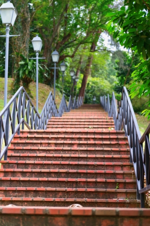 Red stone stairs on in a park with handrail and street lampの写真素材