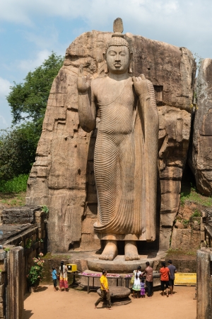 KEKIRAWA, SRI LANKA - APR 16: Pilgrims pray near Avukana standing Buddha statue on Apr 16, 2013 in Sri Lanka. It is 40 feet (12 m) high, has been carved out of a large granite rock in the 5th century.のeditorial素材