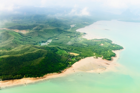 Aerial view of the tropical shore covered by green treesの写真素材