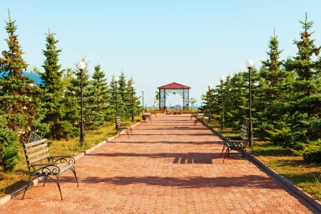 Wide path in nice light  park with benches and summerhouse under clean blue skyの写真素材