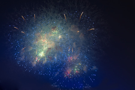 Fireworks in night dark sky with smoke after explosionsの写真素材
