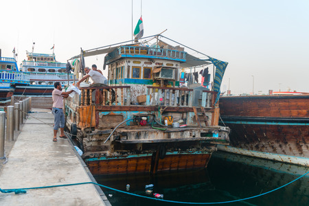 DUBAI, UAE - 16 JULY 2014: Very old and decrepit traditional dhows wooden boat stands moored up at Dubai Creek wharfage, United Arab Emiratesのeditorial素材