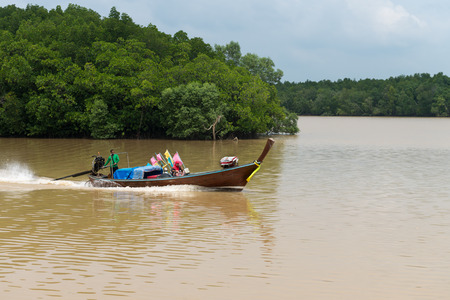 KRABI THAILAND  14 OCT 2014: Local fisherman and his wife cruising along the Krabi River in Thailand in their motorized handmade wooden boat with a load of nets and marker buoys.のeditorial素材