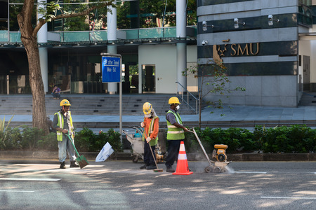 SINGAPORE  02 JUN 2013: Construction workers use specialized equipment to cut a section of pavement on a downtown street.のeditorial素材
