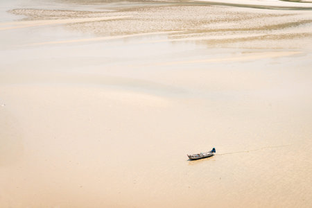 Small, open motorboat, traveling alone over an open, shallow expanse of silty low water.