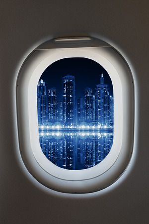 Airplane window from interior of aircraft with modern megapolos city view at night.の写真素材