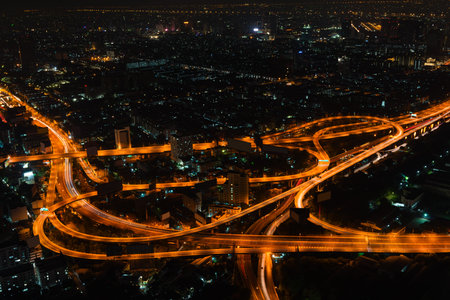 Bangkok's cityscape at night with highrise buildings and a complicated highway interchange,...