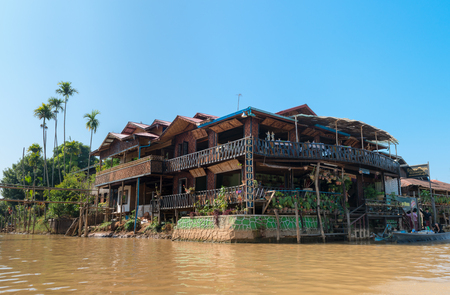 INLE LAKE, MYANMAR - 07 JAN 2014: Traditional old restaurant by the water in Inle lake in Burma with a blue sky.のeditorial素材