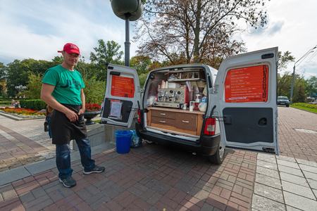 KIEV, UKRAINE - 16 SEP, 2013: Mobile coffee cafe in the city centre with one, smiling, man, serving coffee from the back of his vanのeditorial素材