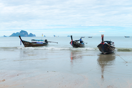 KRABI, THAILAND - 13 OCT 2014: Long boat taxis anchored by rope in shallow water at tranquil Ao Nang beach, Krabi, Thailandのeditorial素材