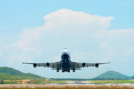Big passenger airplane flying and lifts off at the end of its runway on a hot, sunny day in an airport.の写真素材
