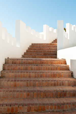 Exterior stairway, constructed of red bricks, with clean, stark white, crenellated walls at a luxury resort hotel.の写真素材