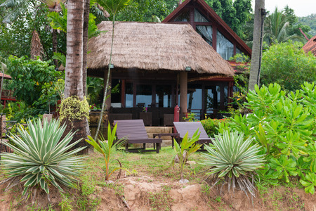 Tropical hotel resort in green nature environment with palm roof and wooden chairsの写真素材