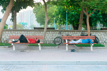 DUBAI, UAE - 16 JUL 2014: Two man are sleeping on benches in early morningのeditorial素材