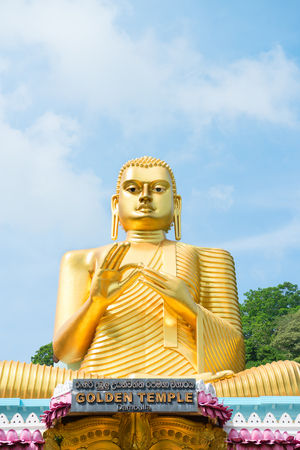 Big golden Buddha statue in wheel-turning pose on the top of Golden temple in Dambulla, Sri Lankaの写真素材