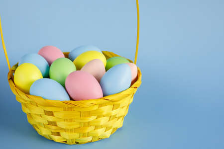 Easter eggs in a yellow basket with copy space for text on blue background.の写真素材