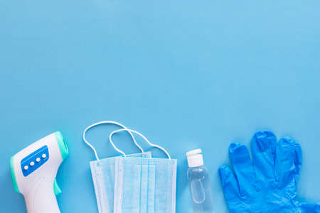 virus protection concept flat lay. Non-contact infrared body thermometer, latex gloves, disposable...
