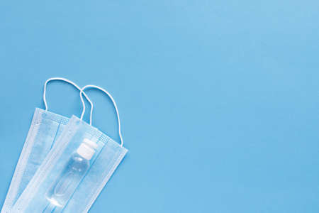virus protection concept flat lay. Disposable face masks and hand sanitizer on blue background with copy space for text.の写真素材