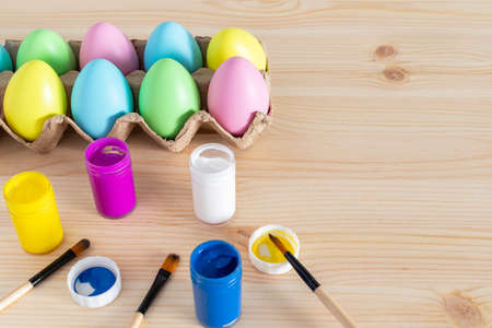 Easter eggs and colored paints with paintbrushes on the table. Easter craft concept.の写真素材