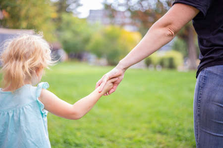 Mother and daughter holding hands. Family love and care concept. Beautiful sunny day.の写真素材