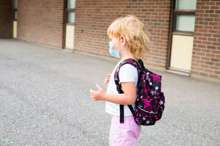 Little pre schooler child in mask with backpack.の写真素材