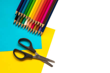 Colorful pencils, scissors on paper and white background. Back to school or craft conceptの写真素材