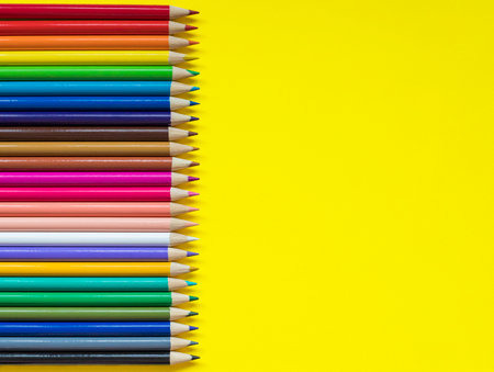Colored pencils on yellow background with copy space for text on one side