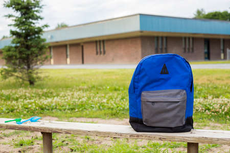 Backpack on bench near school in the park. Back to school concept.の写真素材
