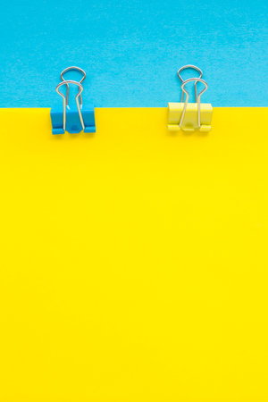 Binder clips on a blue and yellow paper background