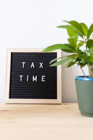 Tax time black felt letter board and flower pot on the table. Business tax return concept.