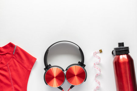 Measuring tape, water bottle, headphones and sportwear on white background. Fitness, sports and workout concept flat lay with copy space.の写真素材