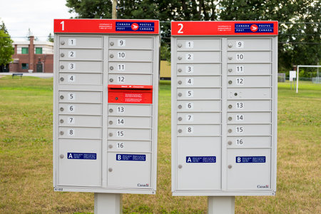Ottawa, Canada - July 20, 2020: Canada Post mail boxes set in the neighborhood community near park with red sign in English and Frenchのeditorial素材