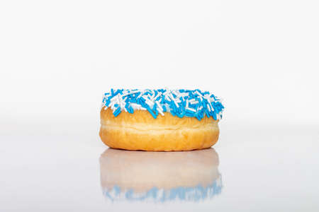 Donut with blue and white sprinkles on white background with reflection and copy space for text.の写真素材