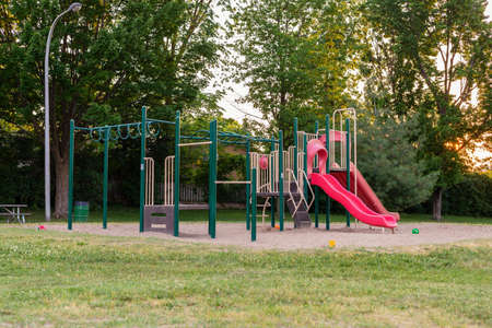 Playground without children in the local public park. Play structure with red slides in the summer...