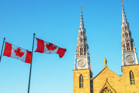 Canadian flags in front of the Notre-Dame Cathedral Basilica in Ottawa, Canada on a sunny day against blue skyのeditorial素材