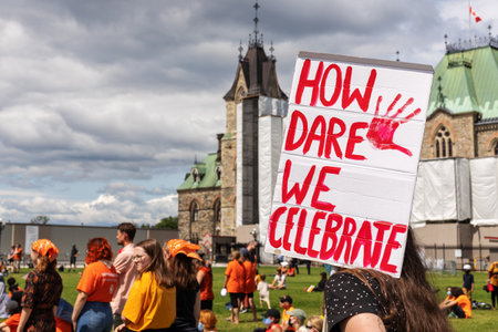 Ottawa, Canada - July 1, 2021: Cancel Canada Day protest rally on Parliament Hill in support of Indigenous people. Every Child Matters. People wearing orange shirts, holding signsのeditorial素材