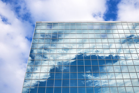 Reflection of blue sky with clouds in tall modern glass building in downtownの写真素材